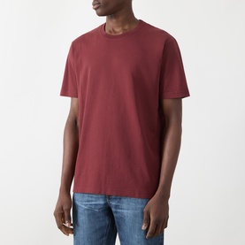 Model wearing Nudie Jeans Uno Everyday T-Shirt in Burgundy, crew neck, short sleeves, paired with blue jeans.