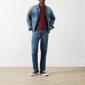 Model wearing Nudie Jeans Uno Everyday T-Shirt in R50 Burgundy, styled with a light blue denim jacket, mid-blue jeans and black trainers.