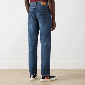 Model wearing Nudie Jeans Rad Rufus Straight-Leg Jeans in Blue Twisted Tracks, mid-wash rigid denim, tobacco stitching, rear view, styled with black