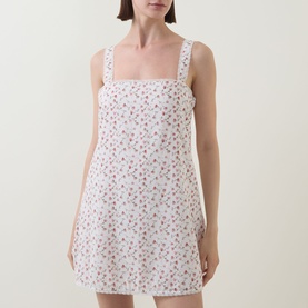 Model wearing Posse Watercolour Floral cotton mini dress with square neckline and wide straps in white floral print.