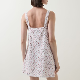 Model wearing Posse Watercolour Floral cotton mini dress, shown from the back, featuring a low back and floral print strappy design.