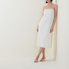 Model wearing Posse cream linen-cotton midi dress with delicate neckline trim, styled with gold strappy heels