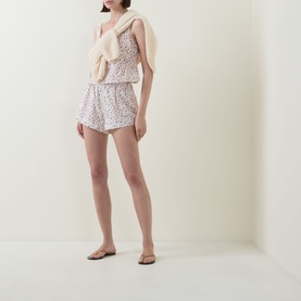 Model wearing Posse Watercolour Floral cotton top with matching floral shorts, cream knit vest, and nude flat sandals