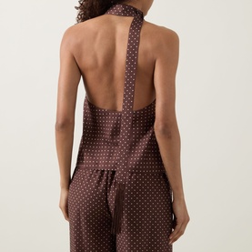 Model wearing Posse Phoebe Polka Dot Blouse in Choc Vanilla, showing open back halter detail with scarf tie, styled with matching wide-leg trousers.