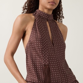 Model wearing Posse Phoebe Polka Dot Blouse in Choc Vanilla, showing scarf neckline detail with fringed edges and sleeveless fit