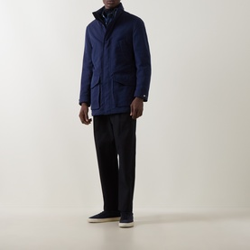 Model wearing B Cucinelli navy casual jacket with stand collar, styled with black trousers and grey trainers.