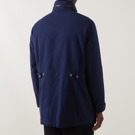 Model wearing Brunello Cucinelli navy casual jacket, rear view, showing button-flap pockets and high collar detail.