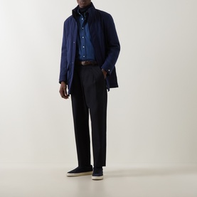 Model wearing B Cucinelli navy casual jacket, styled with dark trousers, blue shirt, and navy trainers.