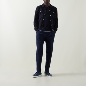 Model wearing B Cucinelli navy calf suede casual jacket with stud detailing, styled with navy trousers and navy trainers.