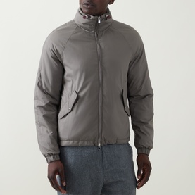 Model wearing Brunello Cucinelli olive casual jacket with funnel neck, zip front, and elasticated cuffs, styled with grey trousers