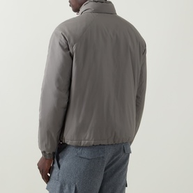 Model wearing Brunello Cucinelli olive casual jacket, rear view, with light blue denim jeans. High collar, zip fastening.