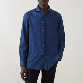 Model wearing B Cucinelli dark wash denim casual shirt with spread collar and button front, styled with black trousers.