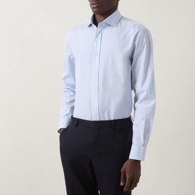 Model wearing B Cucinelli blue cotton casual shirt with spread collar and button placket, styled with navy trousers.