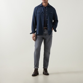 Model wearing Brunello Cucinelli blue wool casual shirt with chest pockets, styled with grey jeans and dark brown leather shoes.