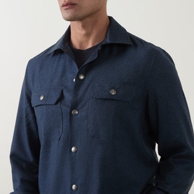Model wearing B Cucinelli blue virgin wool casual shirt with twin chest pockets and silver snap buttons, styled over dark crewneck tee