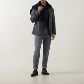 Model wearing B Cucinelli blue wool casual shirt, styled with grey herringbone blazer, grey trousers, navy scarf and brown leather boots.