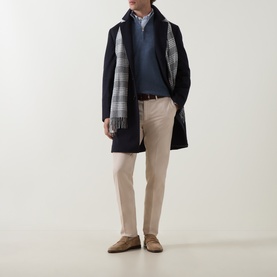 Model wearing B Cucinelli Sand Chino trousers styled with navy coat, grey check scarf and blue knitwear