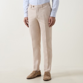 Model wearing B Cucinelli sand cotton chino trousers, styled with a light blue shirt and tan suede loafers.