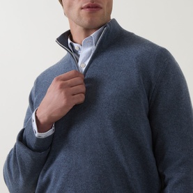 Model wearing B Cucinelli blue cashmere half-zip jumper, styled with a striped shirt underneath, close-up detail view.