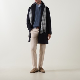 Model wearing Brunello Cucinelli blue cashmere half zip, styled with navy overcoat, grey plaid scarf and beige trousers.