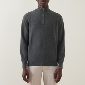 Model wearing Brunello Cucinelli dark green cashmere half-zip jumper with contrast tipping detail, styled with light beige trousers
