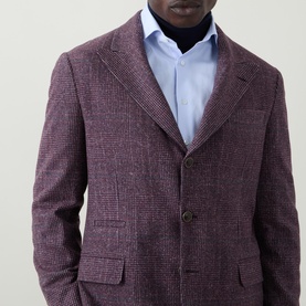 Model wearing B Cucinelli purple silk-wool-cashmere jacket with notch lapels and three buttons, styled with light blue shirt and dark turtleneck