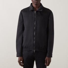 Model wearing black zip-up jacket with leather collar, ribbed cuffs and hem, styled with dark trousers