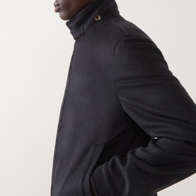 Model wearing dark charcoal wool-blend jacket with high collar and gold-tone button detail, close-up of shoulder and collar area