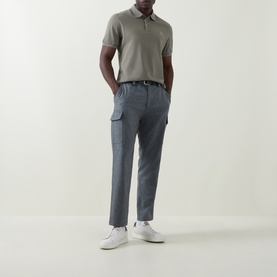 Model wearing Brunello Cucinelli Logo Pique Polo Shirt in Army Wash, styled with grey cargo trousers and white trainers.