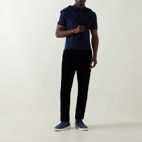 Model wearing B Cucinelli Logo Pique Polo Shirt in Cadet, styled with black trousers and grey slip-on trainers