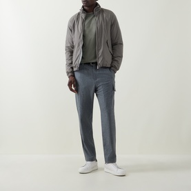 Model wearing B Cucinelli Contrast Trim Jersey T-Shirt in Dark Green, styled with grey cargo trousers, a taupe jacket and white trainers.