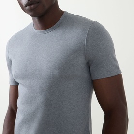 Model wearing Brunello Cucinelli Solid Regular Fit T-Shirt in mid grey, round neck, short sleeves, close-up torso view.