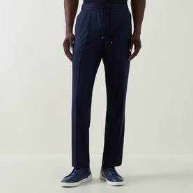 Model wearing Brunello Cucinelli navy blue wool drawstring trousers with side seam detail, styled with light blue loafers