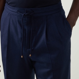 Model wearing Brunello Cucinelli Blu Marina virgin wool trousers with pleat front, drawstring waist, and side pockets