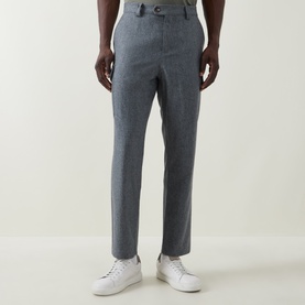 Model wearing B Cucinelli grey virgin wool trousers with button waistband detail, styled with white trainers