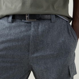 Model wearing Brunello Cucinelli grey virgin wool trousers with cargo pocket detail, styled with a dark belt and sage green top.