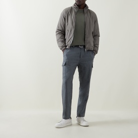 Model wearing B Cucinelli grey virgin wool cargo trousers, styled with a taupe padded jacket, olive top and white trainers.