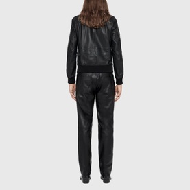 Model wearing All Saints black croc-embossed leather bomber jacket, styled with matching black leather trousers, rear view
