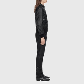 Model wearing All Saints black leather bomber jacket, styled with matching black slim trousers and black boots, side profile view.