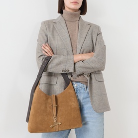 Model carrying Strathberry Kite Suede Hobo Bag in Toffee/Espresso with gold-tone hardware, styled with grey blazer and beige turtleneck