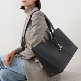 Model carrying Strathberry Kite Leather Tote Bag in black grained leather, gold-tone hardware, double shoulder straps, styled with grey blazer and