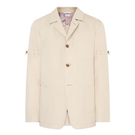 Thom Browne beige cotton blazer with three-button front, tab sleeve detail, and striped lining visible at collar.