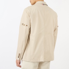 Model wearing Thom Browne beige cotton blazer, back view, with tricolour collar detail and decorative sleeve buttons.
