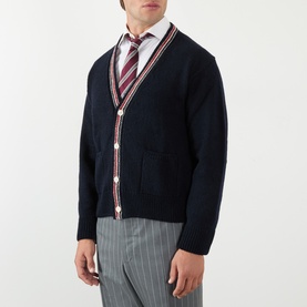Model wearing Thom Browne Navy Cardigan in wool-mohair blend, with red and white trim detail, styled with striped tie and grey trousers.