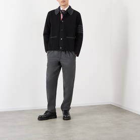 Model wearing Thom Browne black wool casual jacket with 4-bar stripe detail, styled with grey trousers and black loafers.