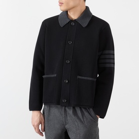 Model wearing Thom Browne black wool casual jacket with contrast collar, 4-bar stripe sleeve detail, and button front, styled with grey trousers.