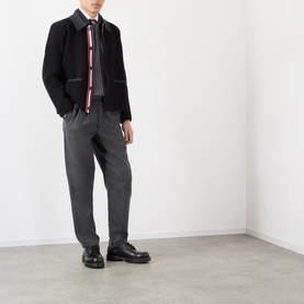 Model wearing Thom Browne black wool casual jacket with red and white stripe trim, styled with grey trousers and black leather shoes.
