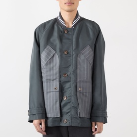 Model wearing Thom Browne Tech Field Jacket in dark grey with contrast pinstripe panels, ribbed collar tipping, and brown button fastening.