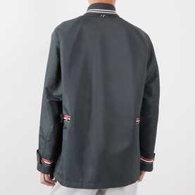 Model wearing Thom Browne Tech Field Jacket in Dark Grey, rear view, showing signature stripe grosgrain tabs and tipped shawl collar detail.