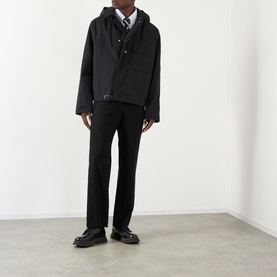 Model wearing Thom Browne Mariner Technical Jacket in black with detachable hood, styled with black trousers and leather shoes.